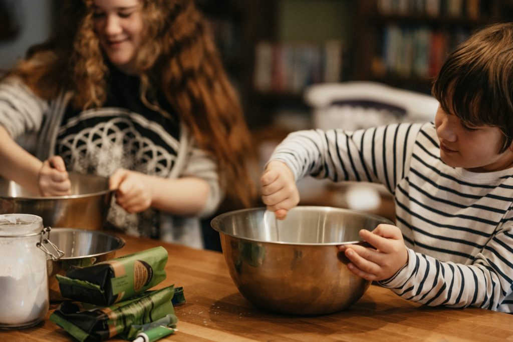 child in black and white striped long sleeve shirt holding stainless steel bowl